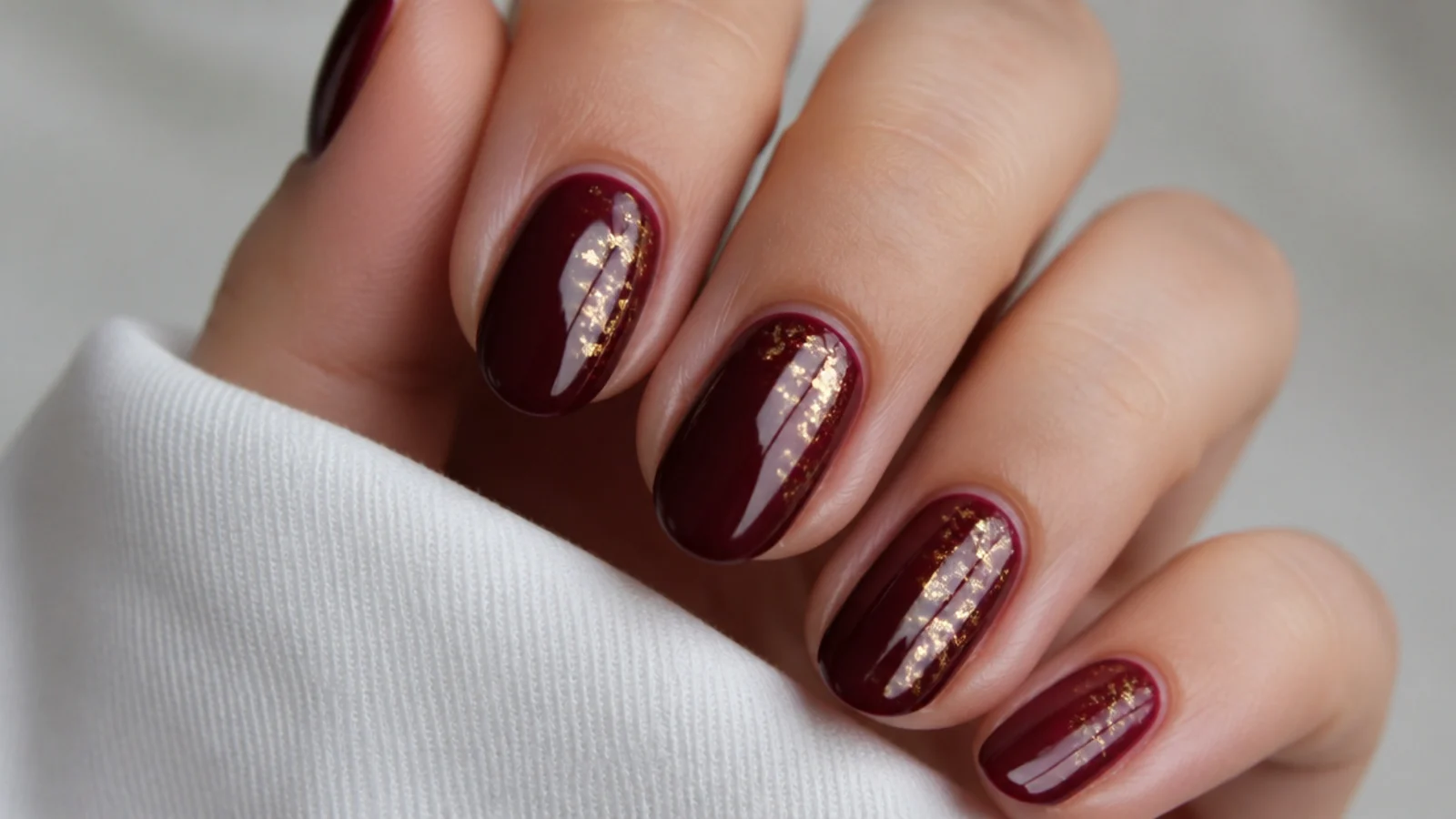 Deep merlot dark feminine nails with fine gold flake accents
