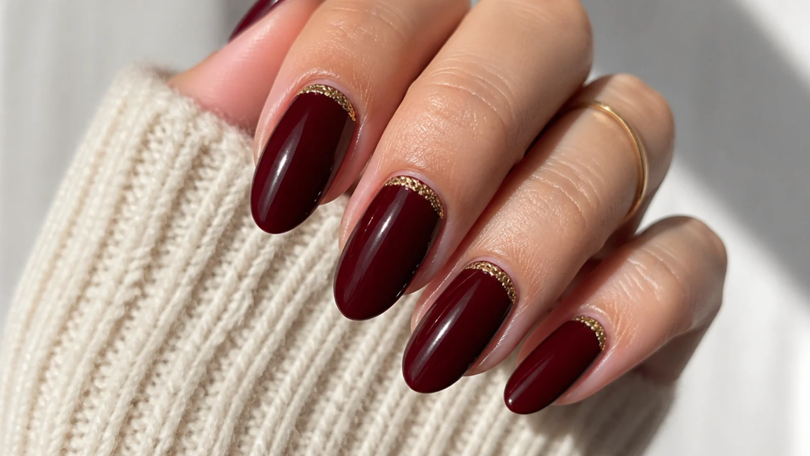 Deep bordeaux dark feminine nails with a fine 3D gold cuff at the cuticle
