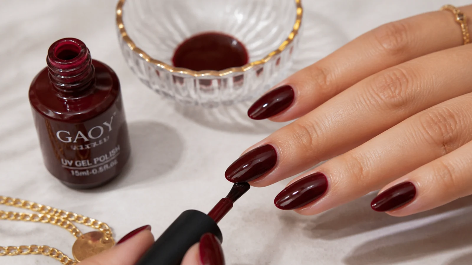 At-home dark feminine gel supplies with a deep oxblood nail mid-application