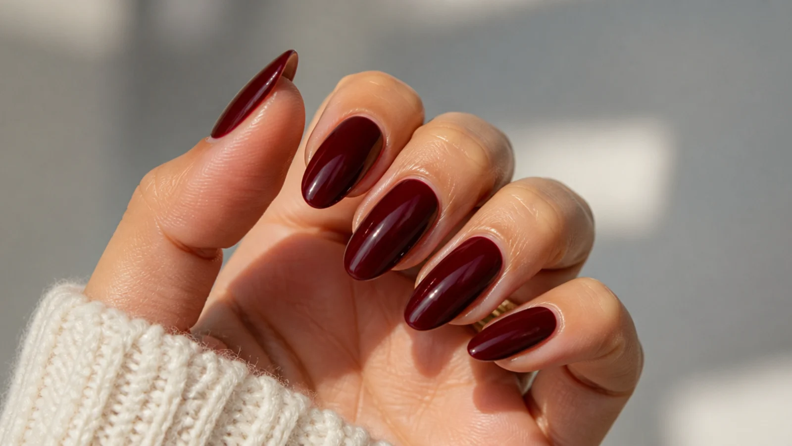 Deep oxblood dark feminine nails on an almond shape with a glossy finish
