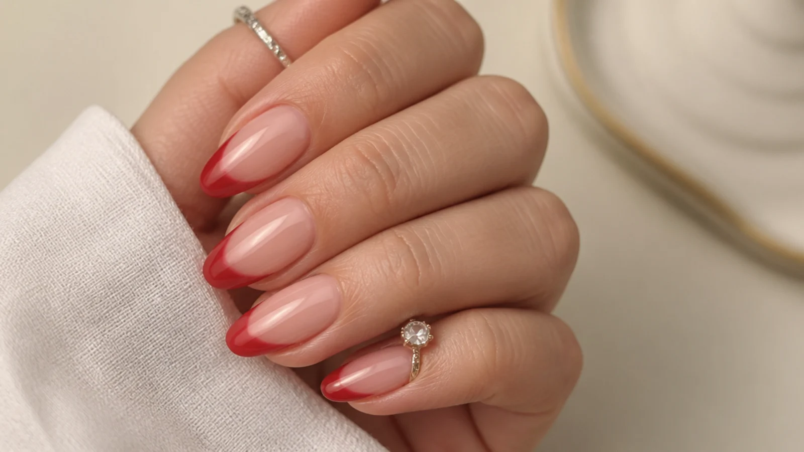 Sheer warm red nails with the natural nail showing through on almond tips