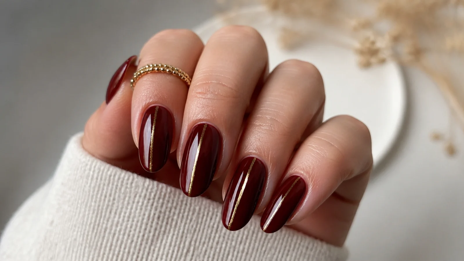 Oxblood red nails with a thin gold foil line down the center