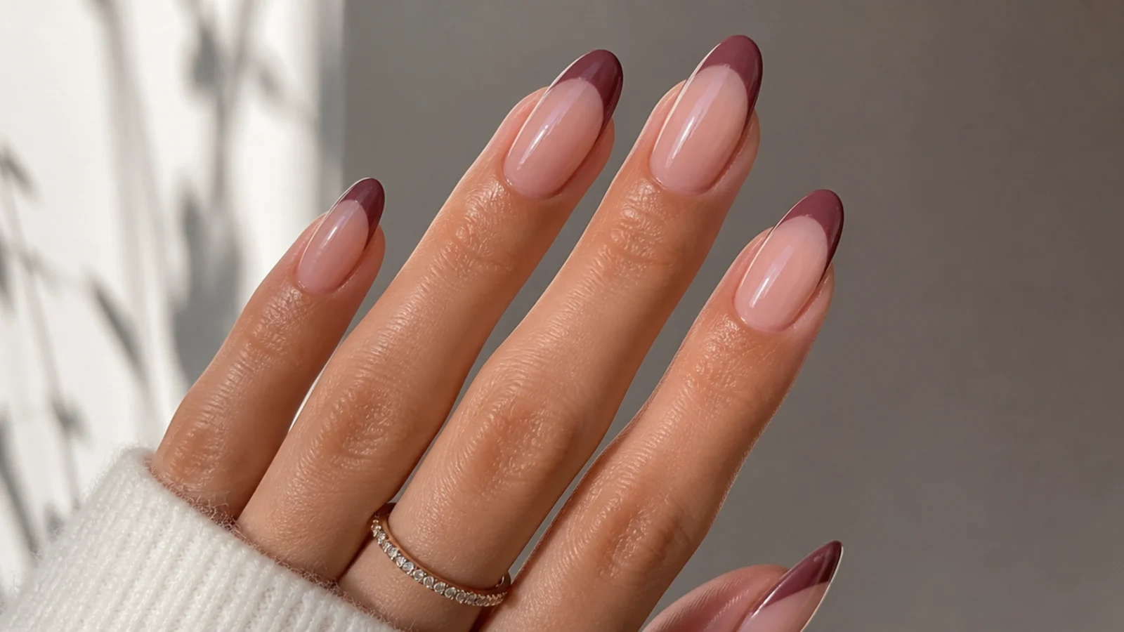 Dark mauve French tip nails on a sheer nude base, almond shape