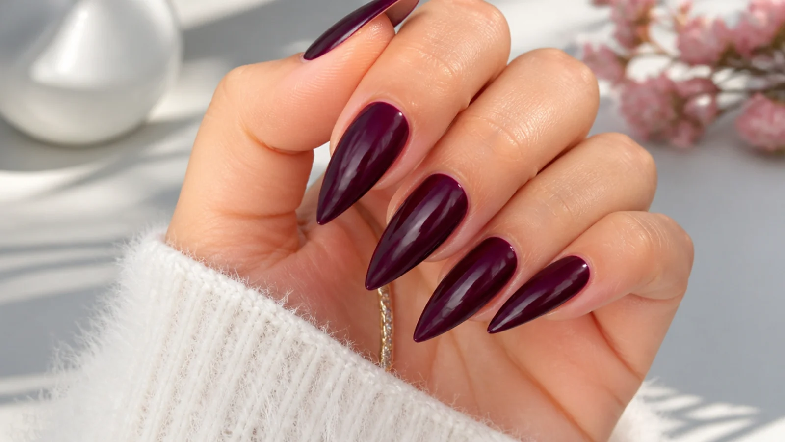 Dark blackberry purple nails on a long stiletto shape, glossy finish