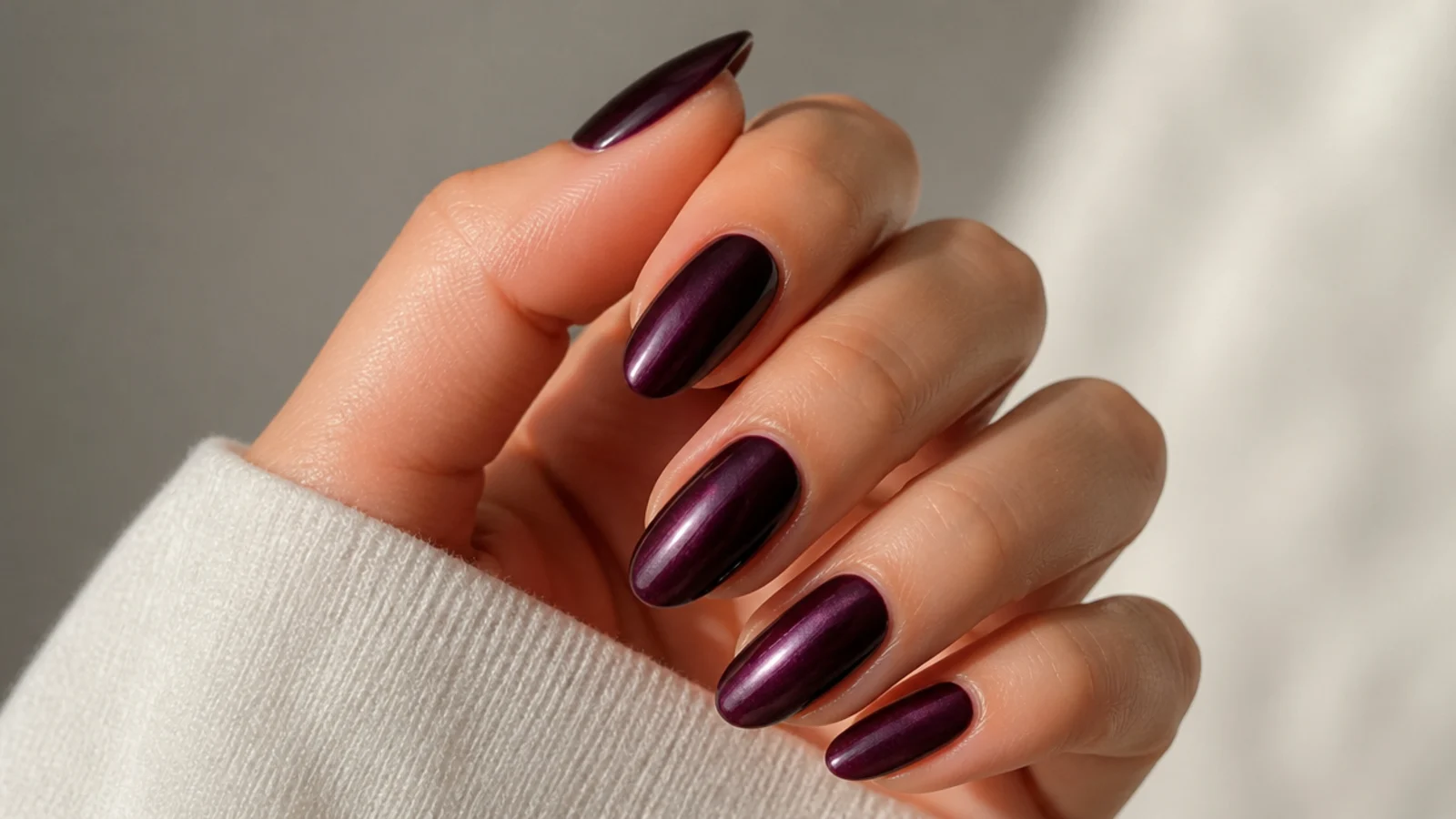 Deep plum nails with a subtle chrome sheen on almond shape