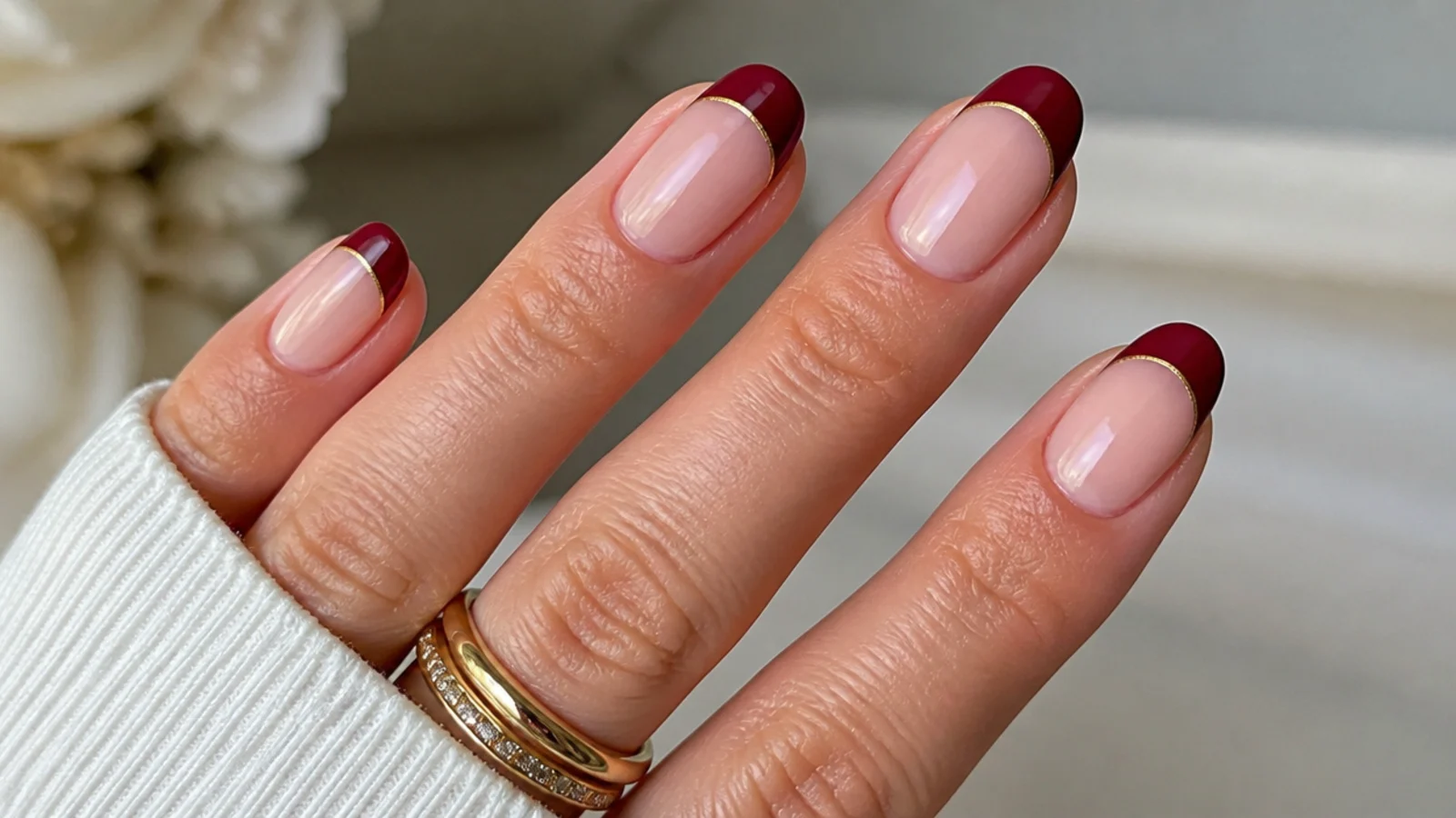 Sheer nude nails with a burgundy French tip lined in fine gold