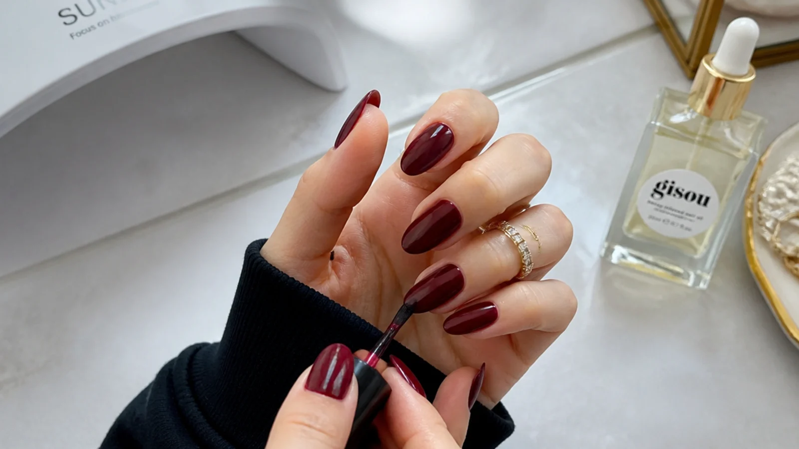Deep oxblood gel being applied at home with a lamp and cuticle oil