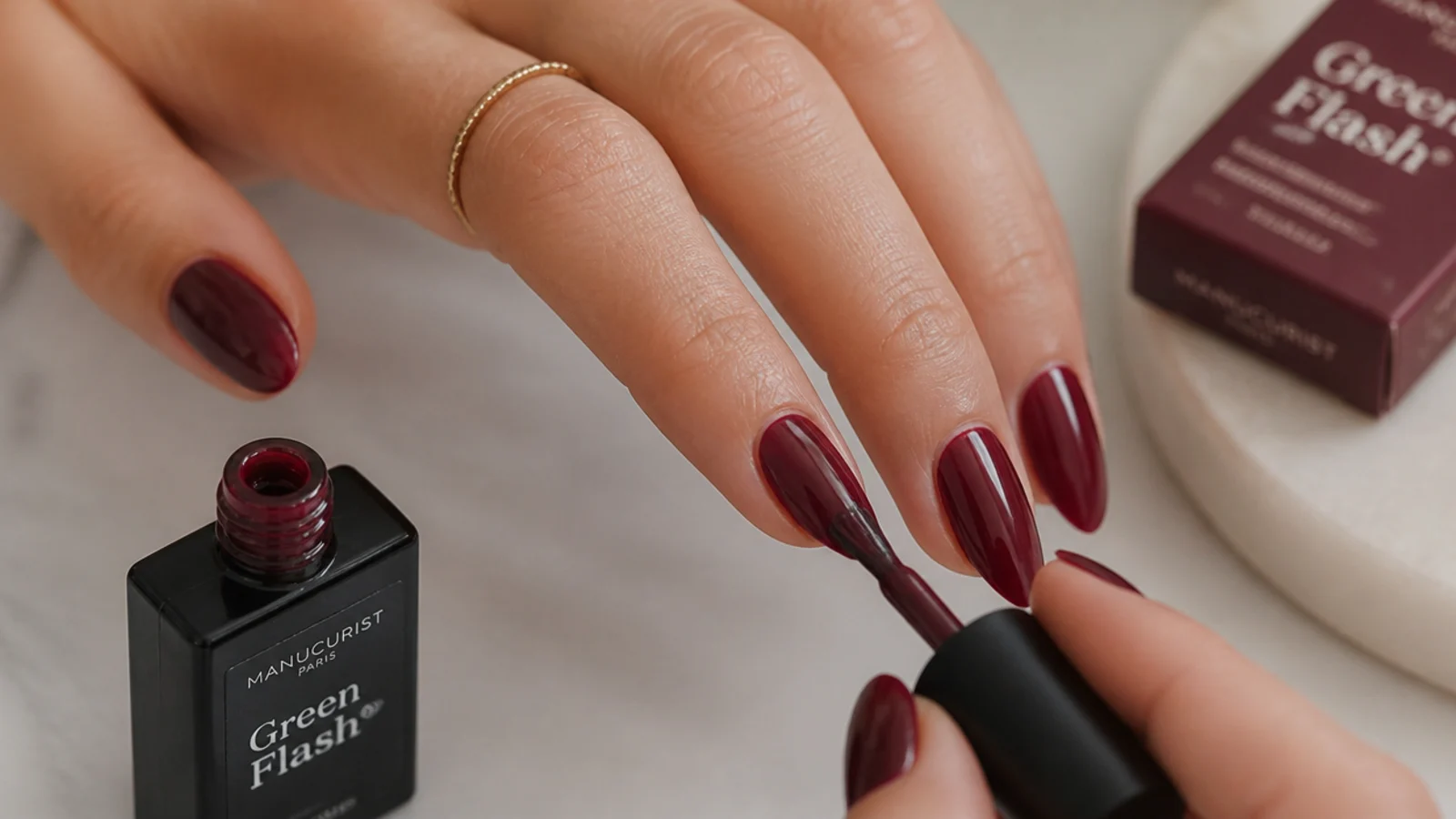 Dark feminine gel supplies with a deep berry nail mid-application