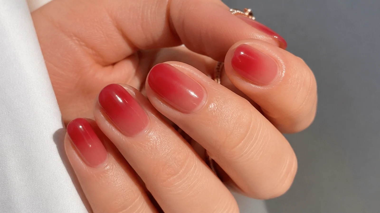 Short almond nails with a sheer warm red jelly wash on a natural base