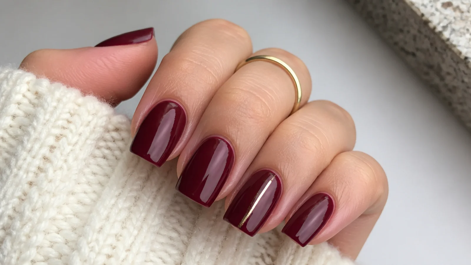 Short coffin nails in deep wine red with a thin gold line on one nail