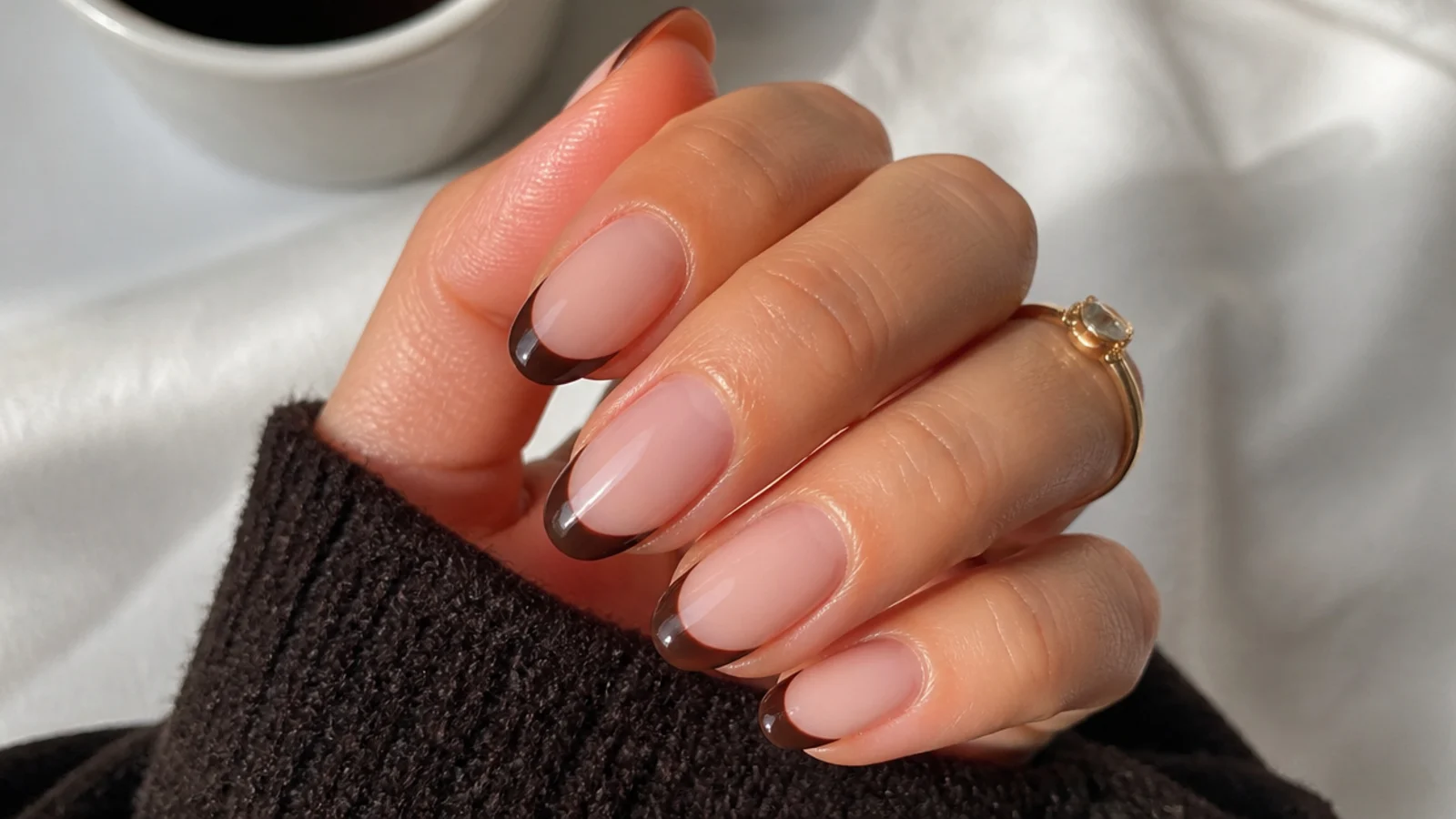 Short almond nails with a sheer nude base and dark espresso brown tips