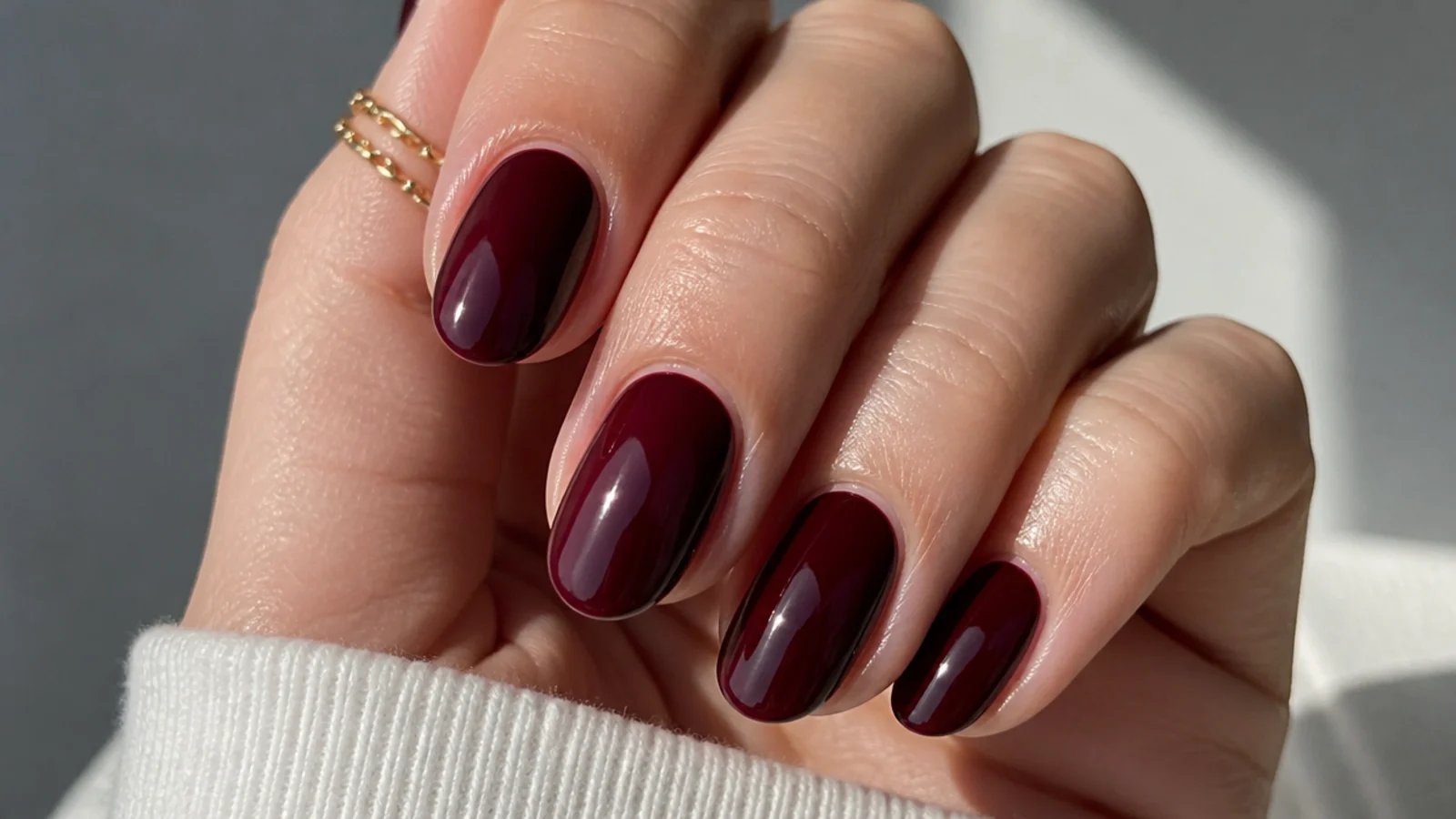 Short almond nails in glossy black cherry red with a glassy shine