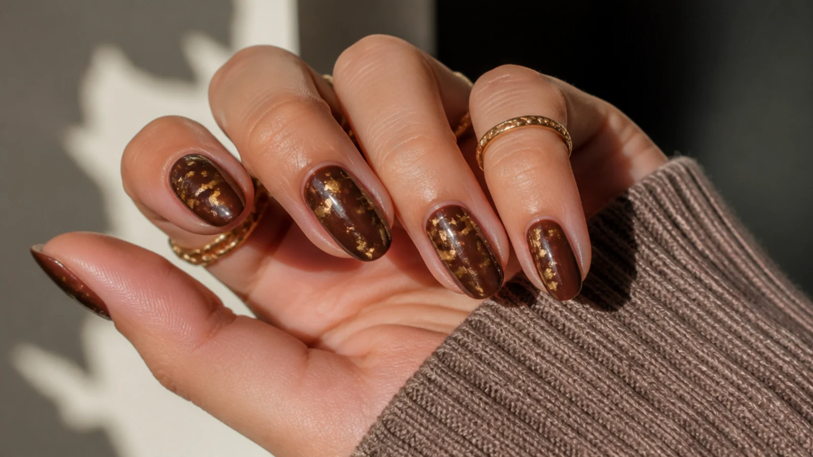 Short almond nails in chocolate brown with flecks of gold foil