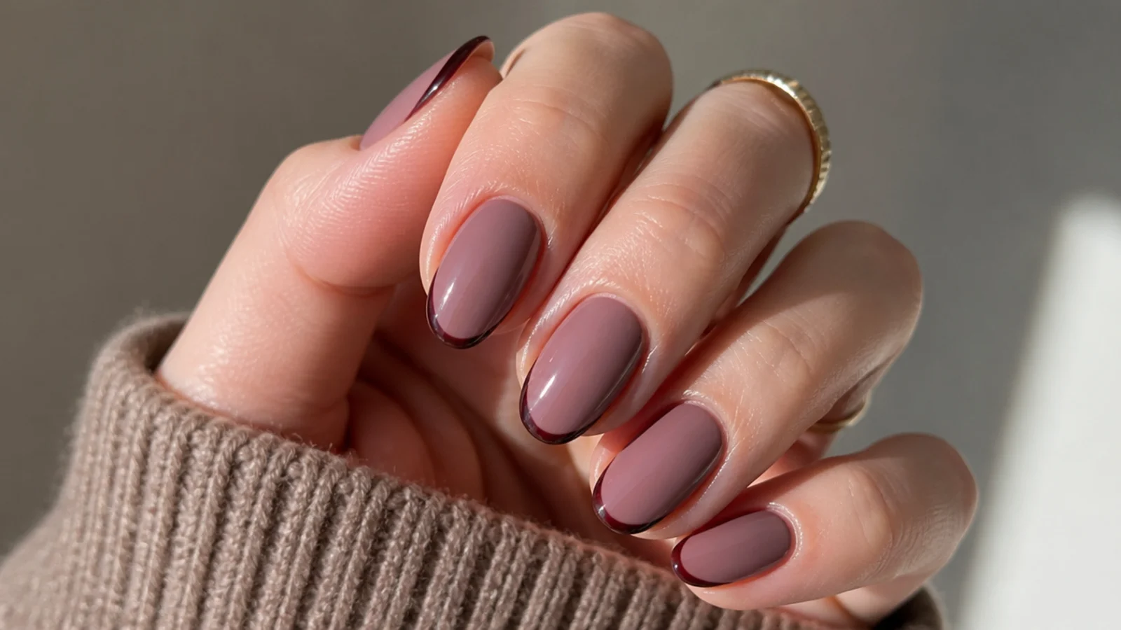 Short almond nails with a mauve base and thin dark tip on the edge