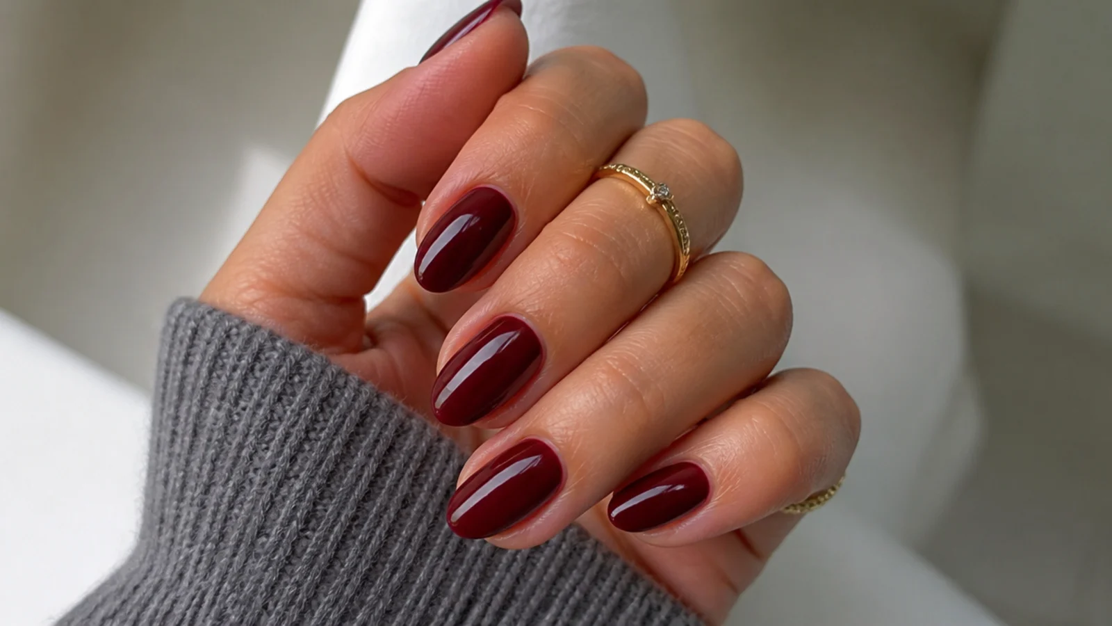 Short almond nails in deep oxblood with a glossy finish on a manicured hand