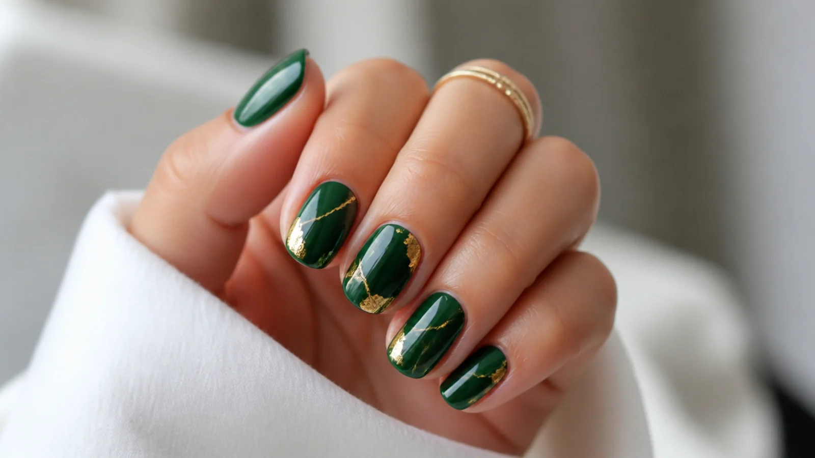 Dark emerald green nails with thin gold foil lines and accents