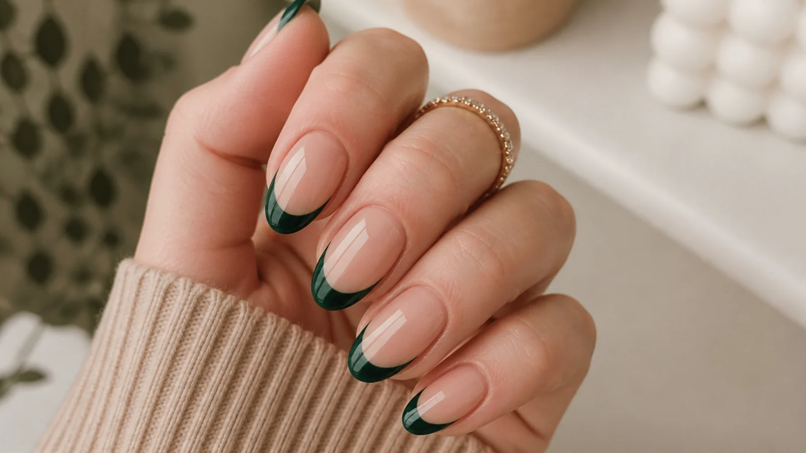 Nude nails with dark emerald green french tips on an almond shape