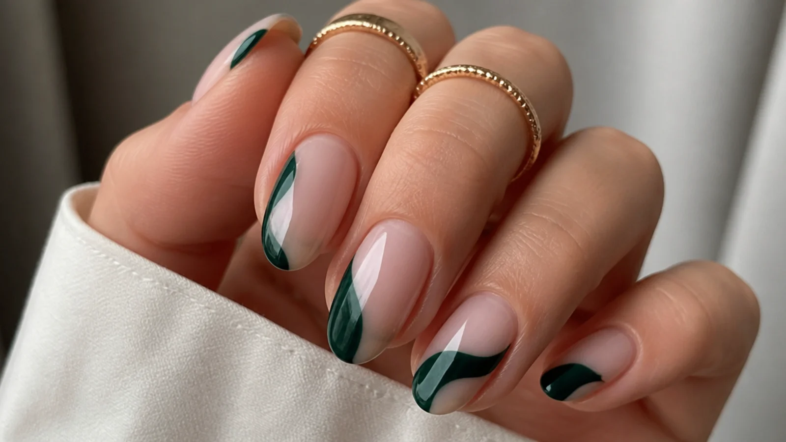 Sheer nude nails with dark emerald green negative-space accents