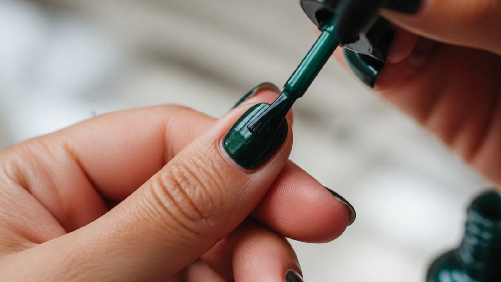 Emerald gel layered over a dark base coat mid-application on a nail