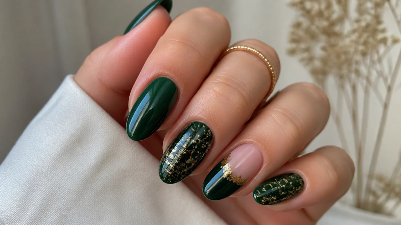 Emerald green nails with gold foil accents on an almond shape