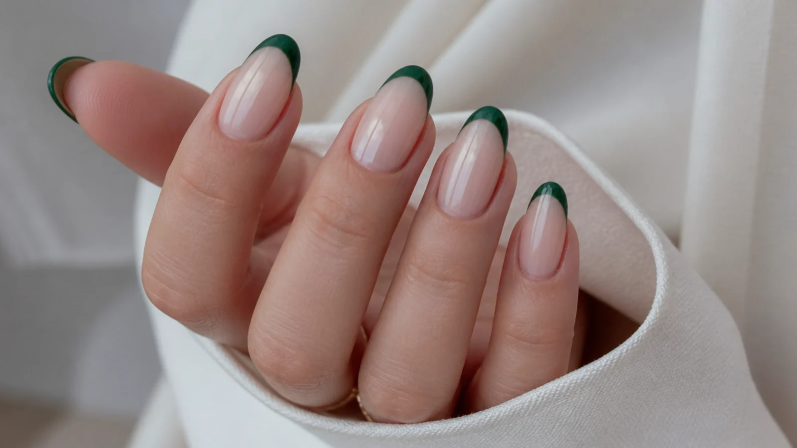 Nude nails with dark forest green french tips on an almond shape