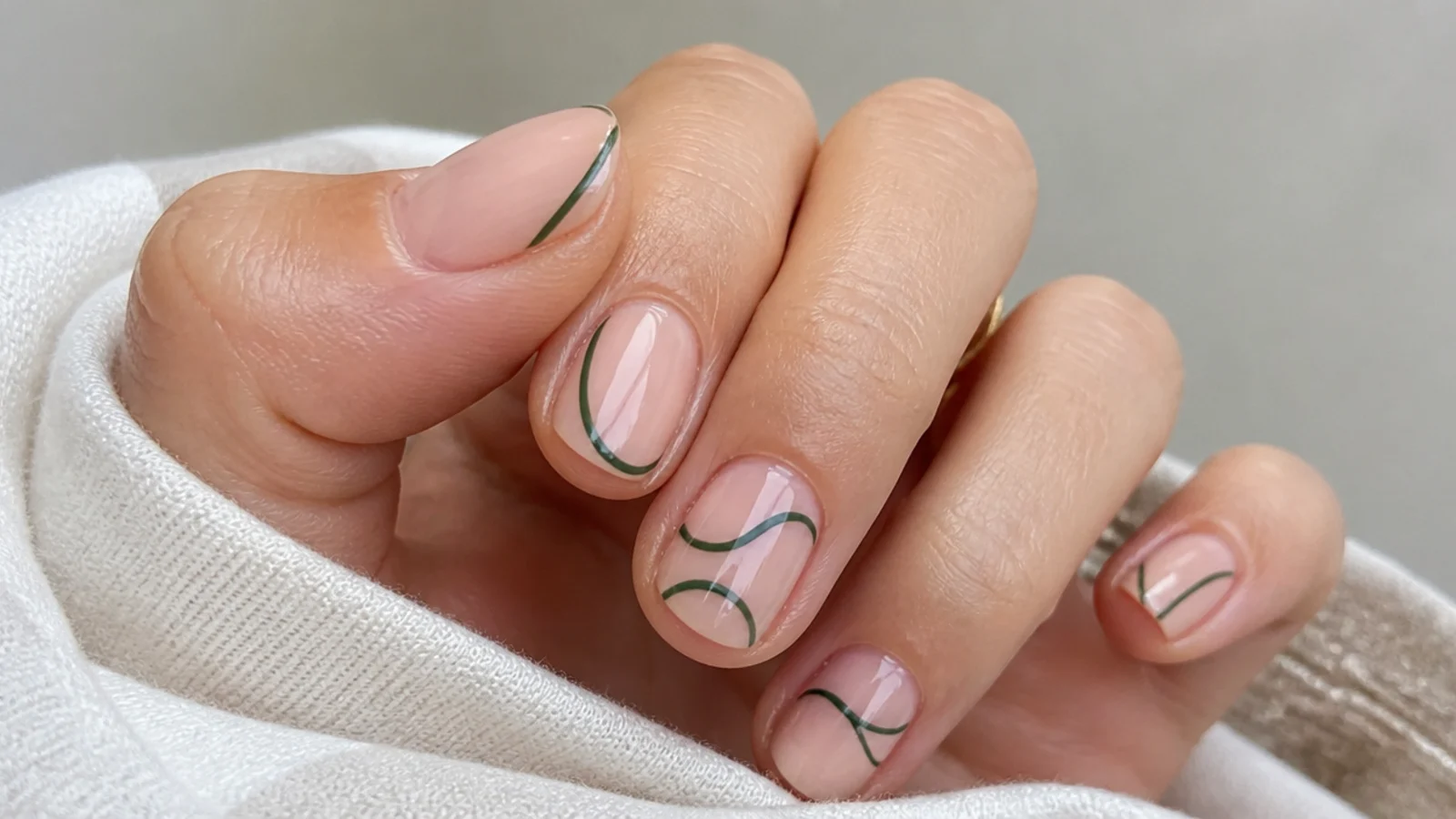 Sheer nude nails with thin dark green line art on short nails