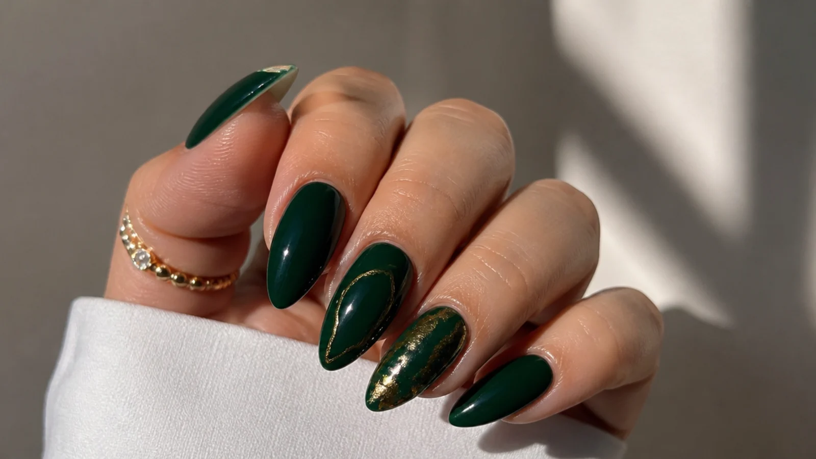 Deep saturated emerald acrylic nails on a long almond shape with high gloss