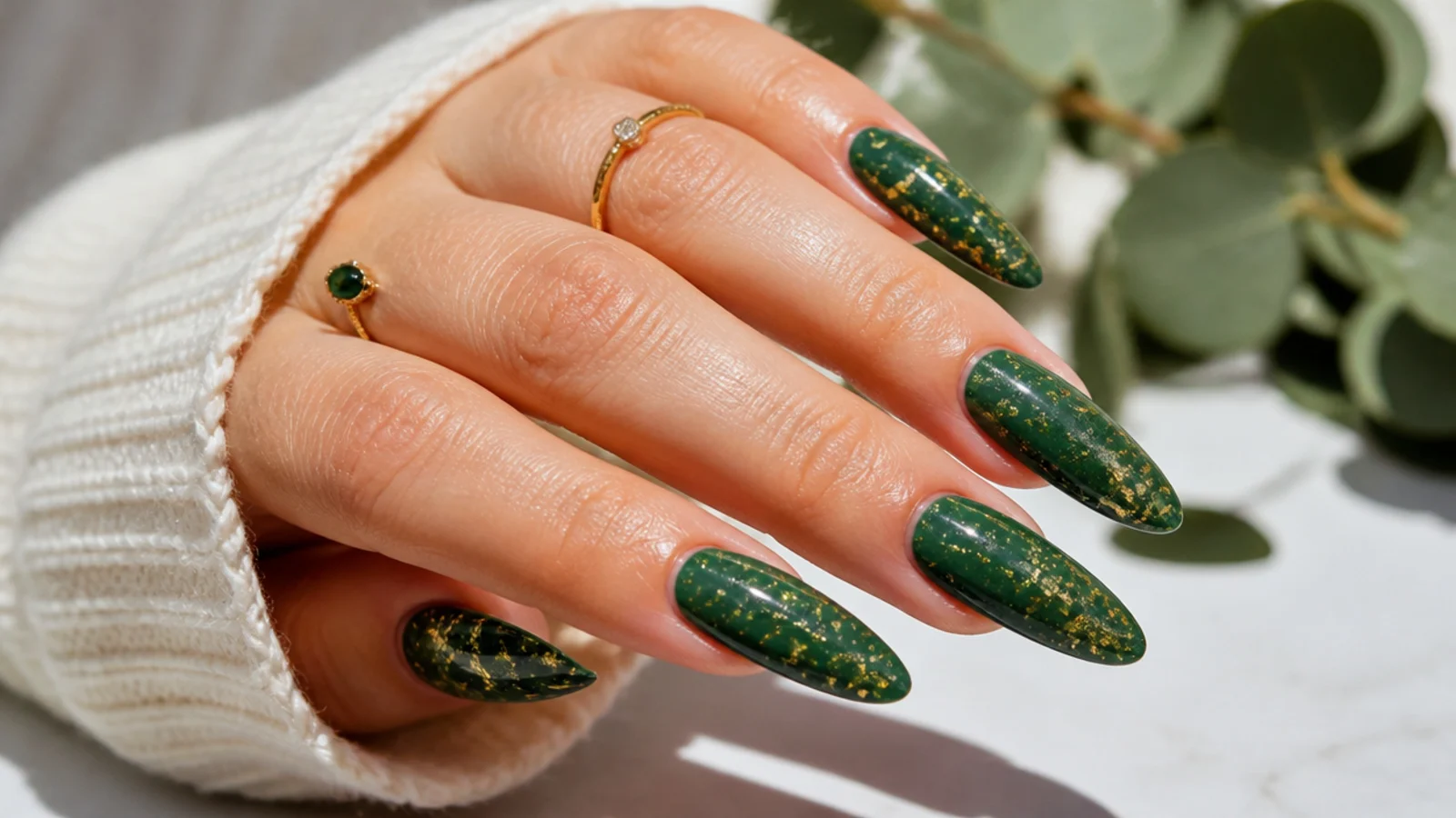 Deep forest green nails scattered with fine gold foil flecks