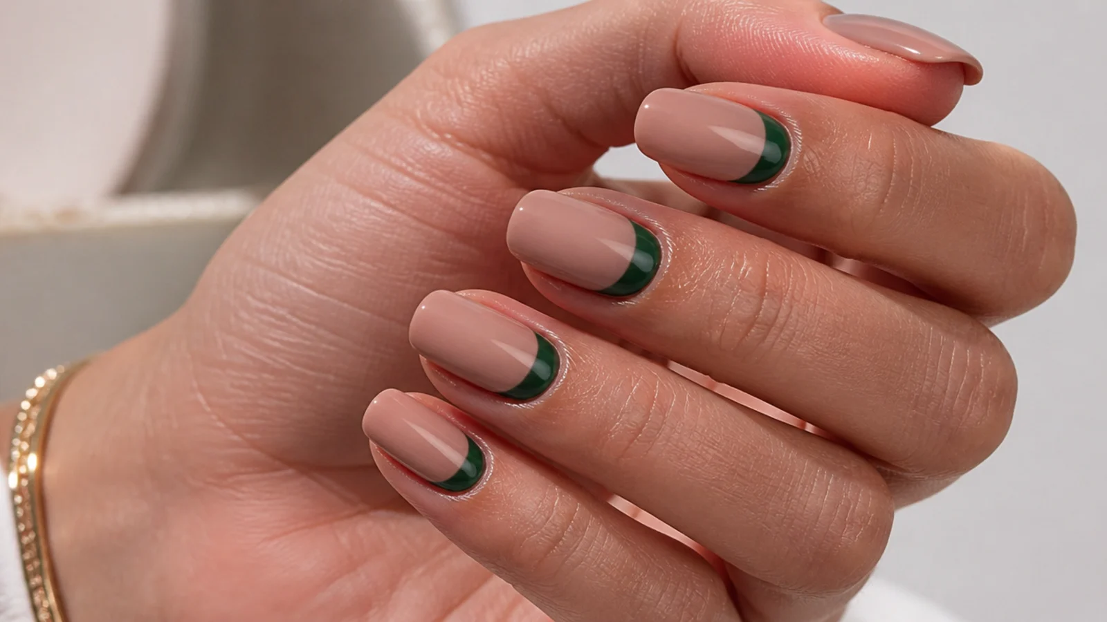 Nude nails with a dark forest green half-moon at the cuticle