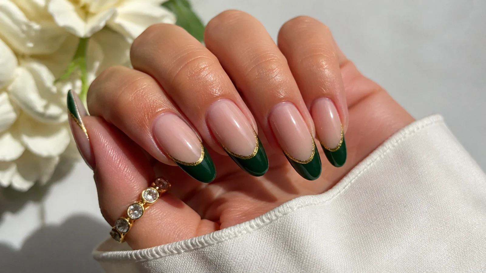 Nude almond nails with forest green french tips lined in gold