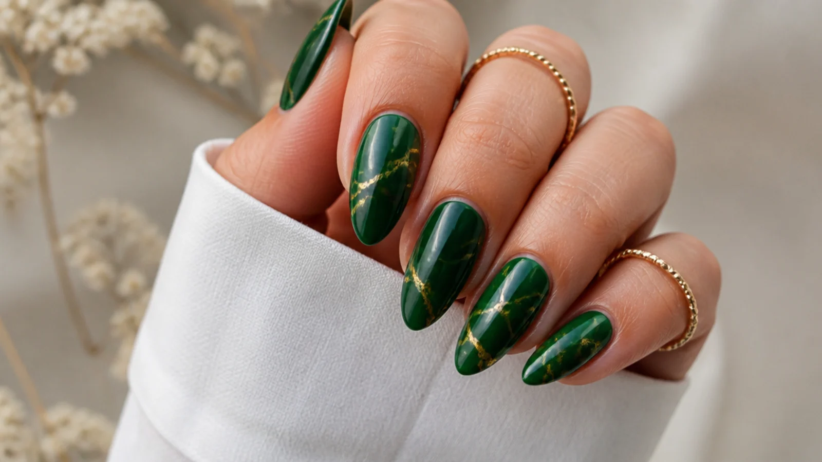 Dark emerald almond nails with thin gold marble veins