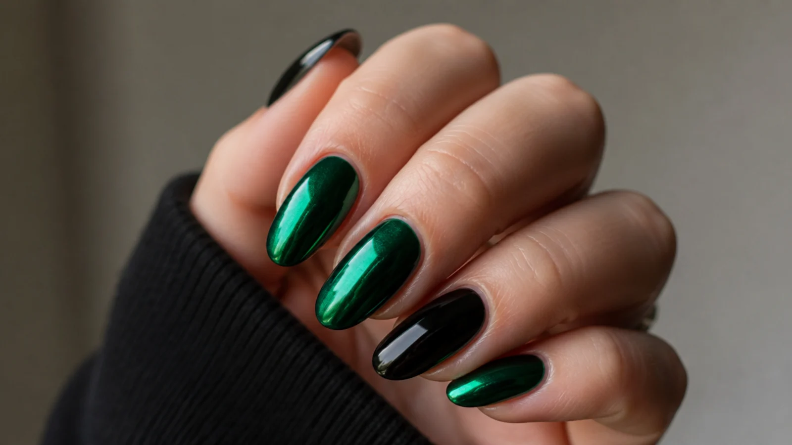 Mirror-finish emerald and black chrome nails reflecting light