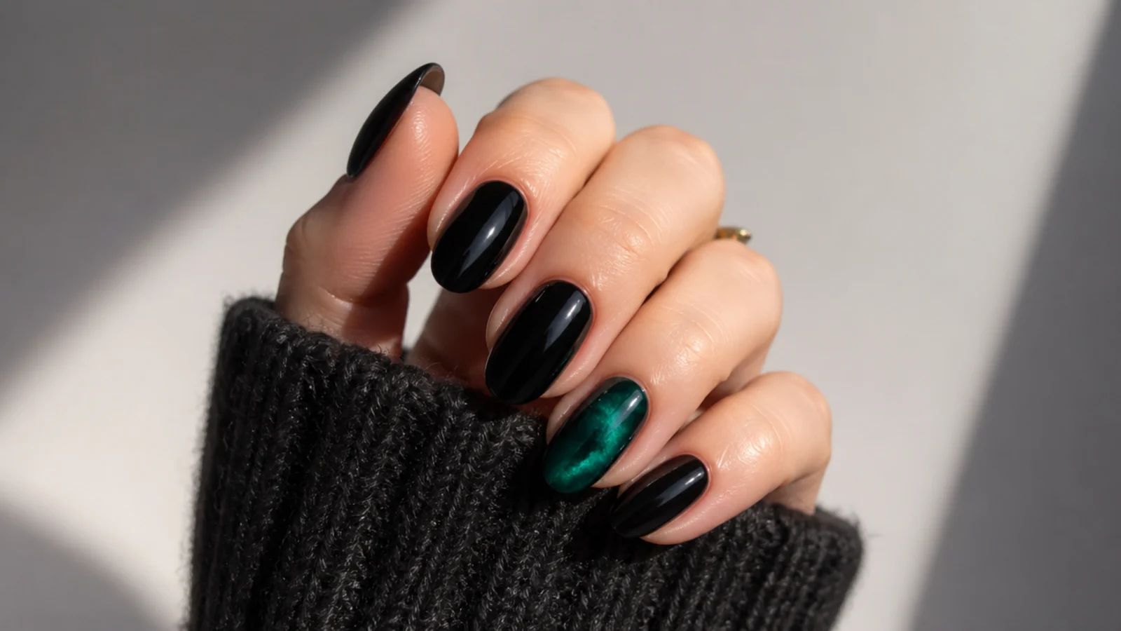 Glossy black nails with one emerald green accent nail
