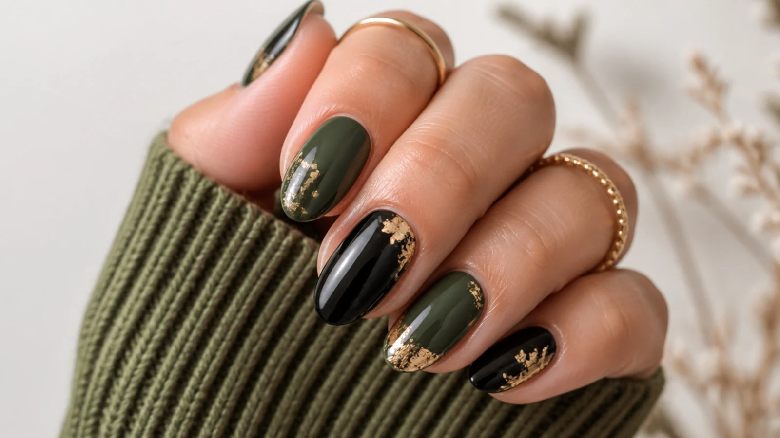 Forest green and black nails with scattered gold foil flecks