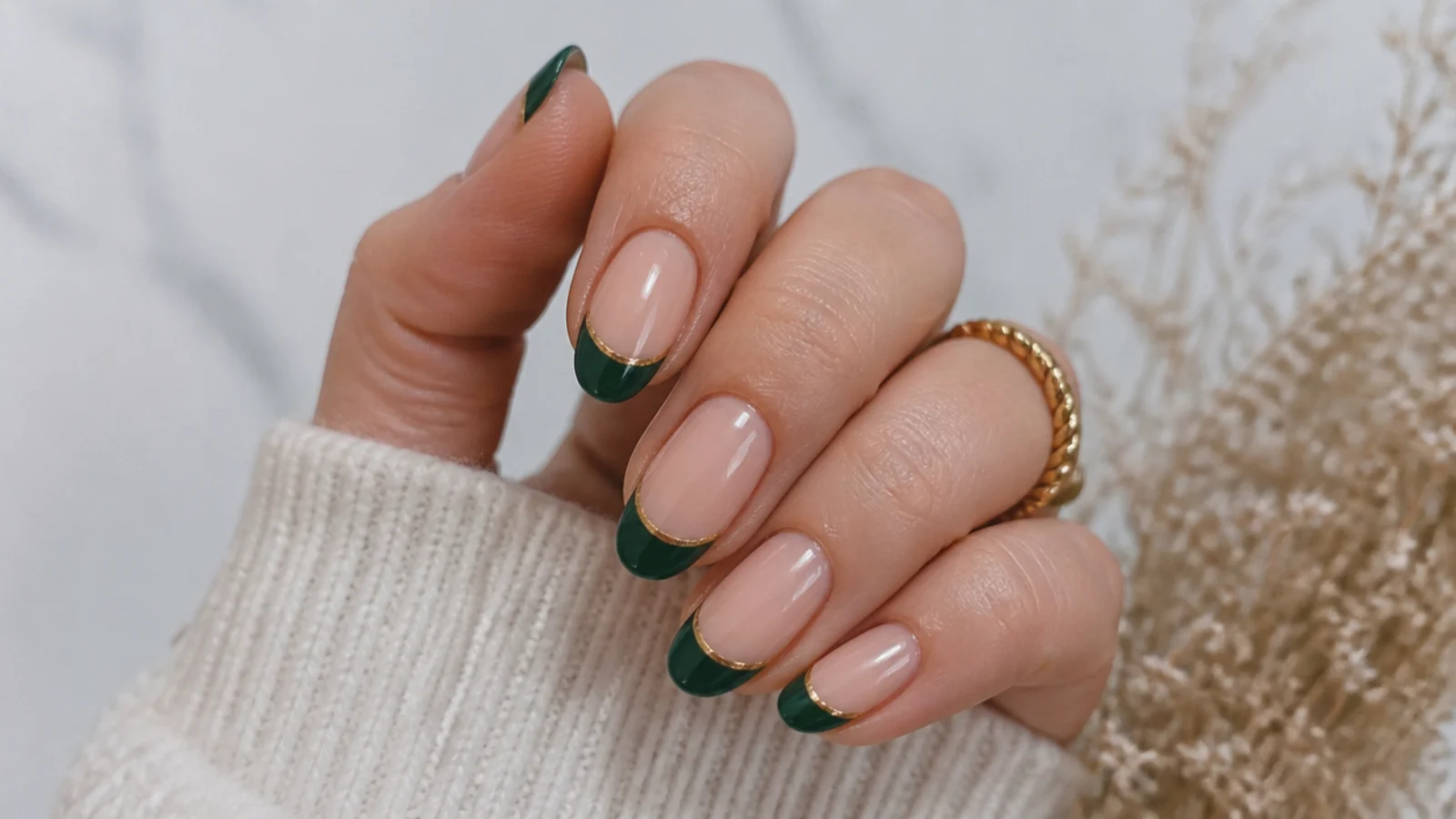 Nude nails with forest green french tips lined in thin gold on almond shapes