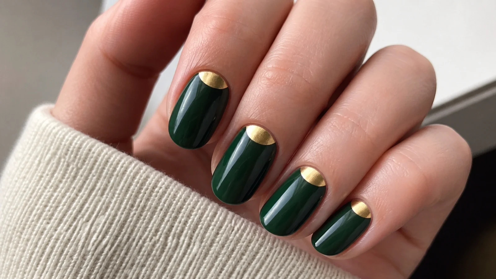 Deep green nails with a solid gold half-moon at the base