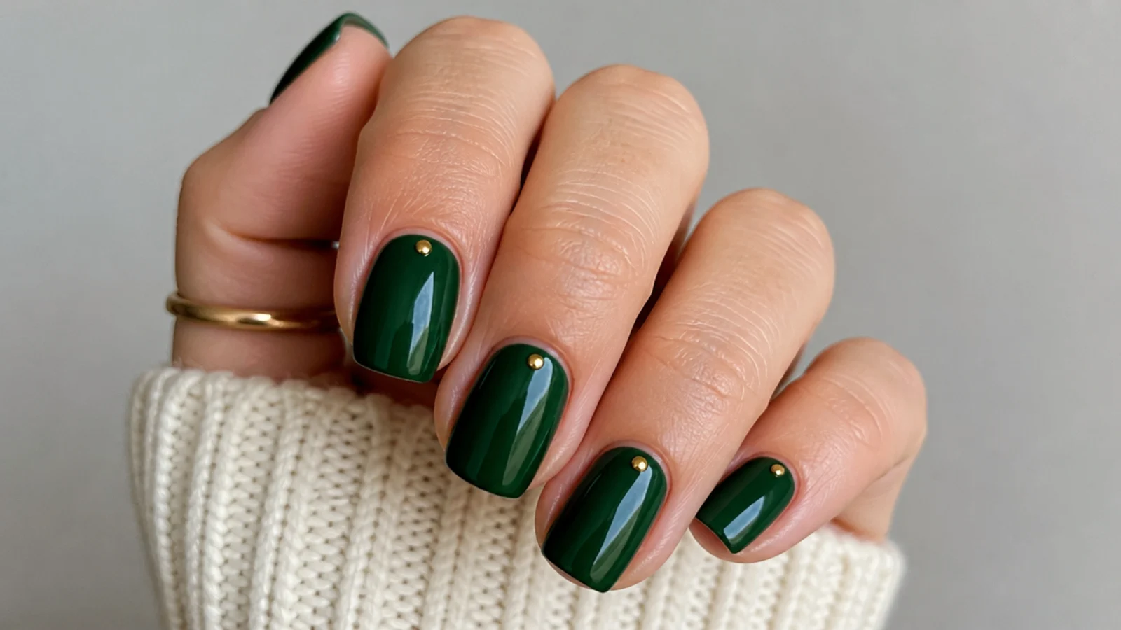 Short squoval emerald nails with a single gold dot at each cuticle