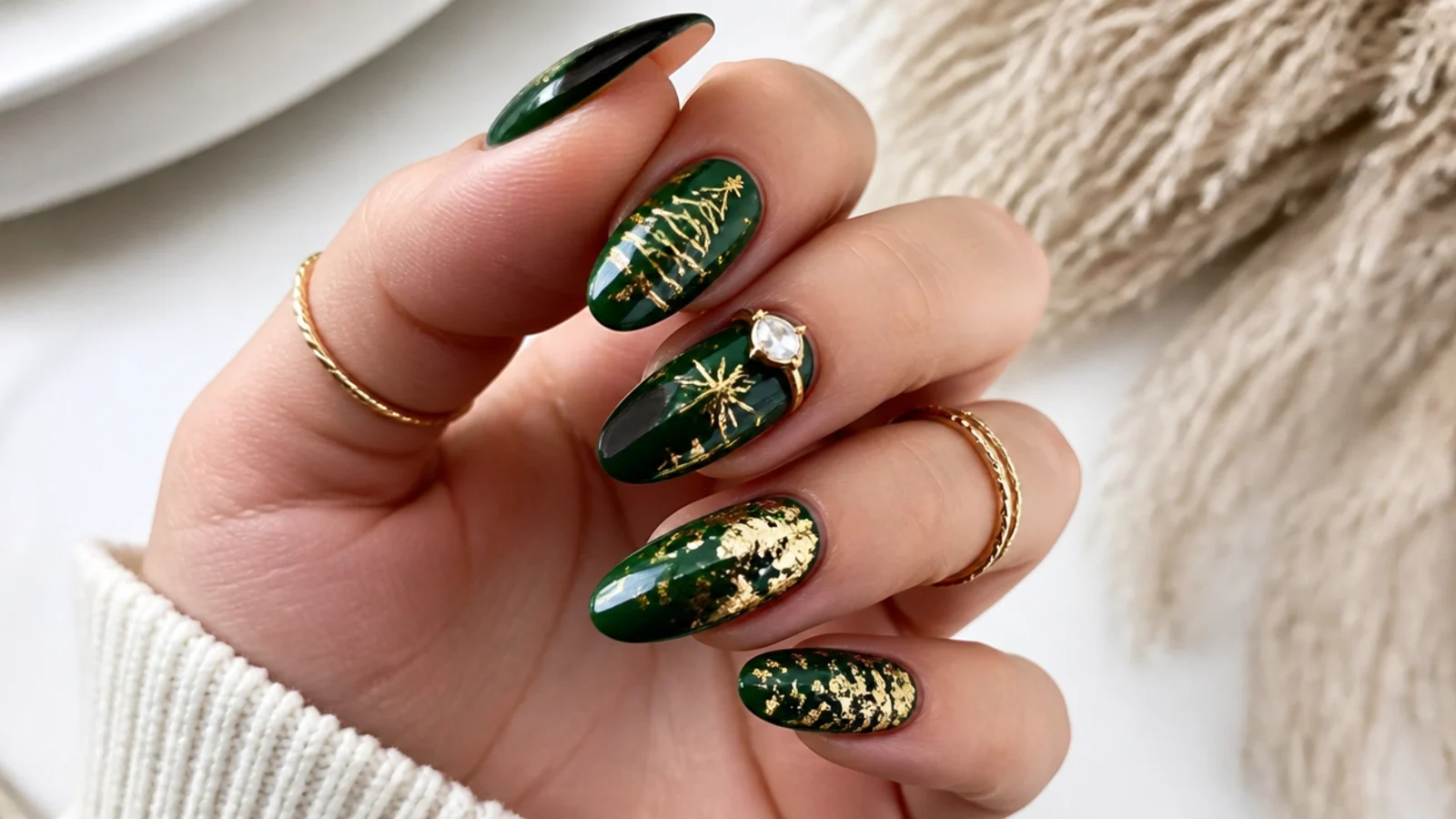 Dark emerald green Christmas nails with gold foil accents on an almond shape