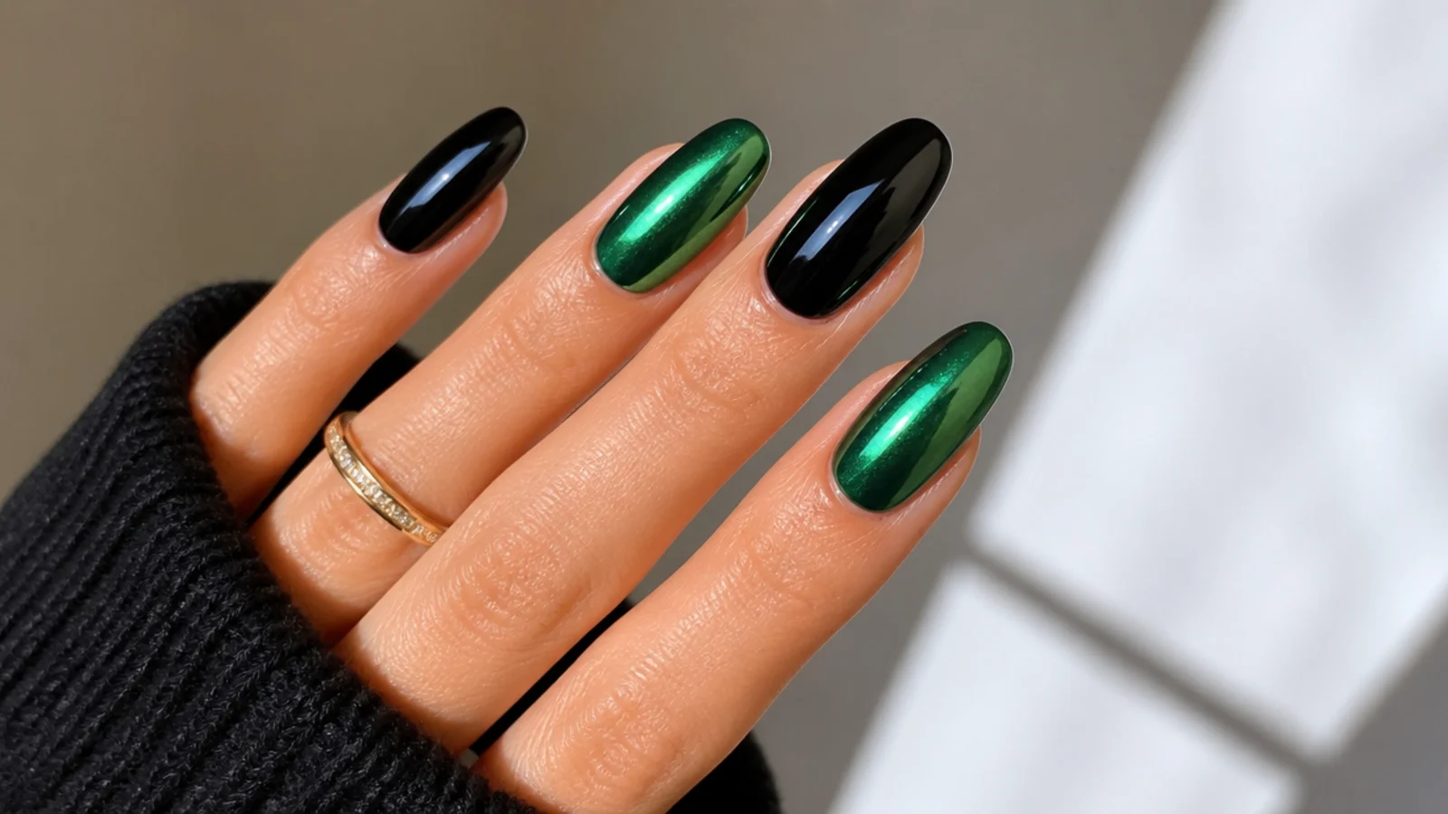 Alternating black and dark green chrome nails with a mirror shine