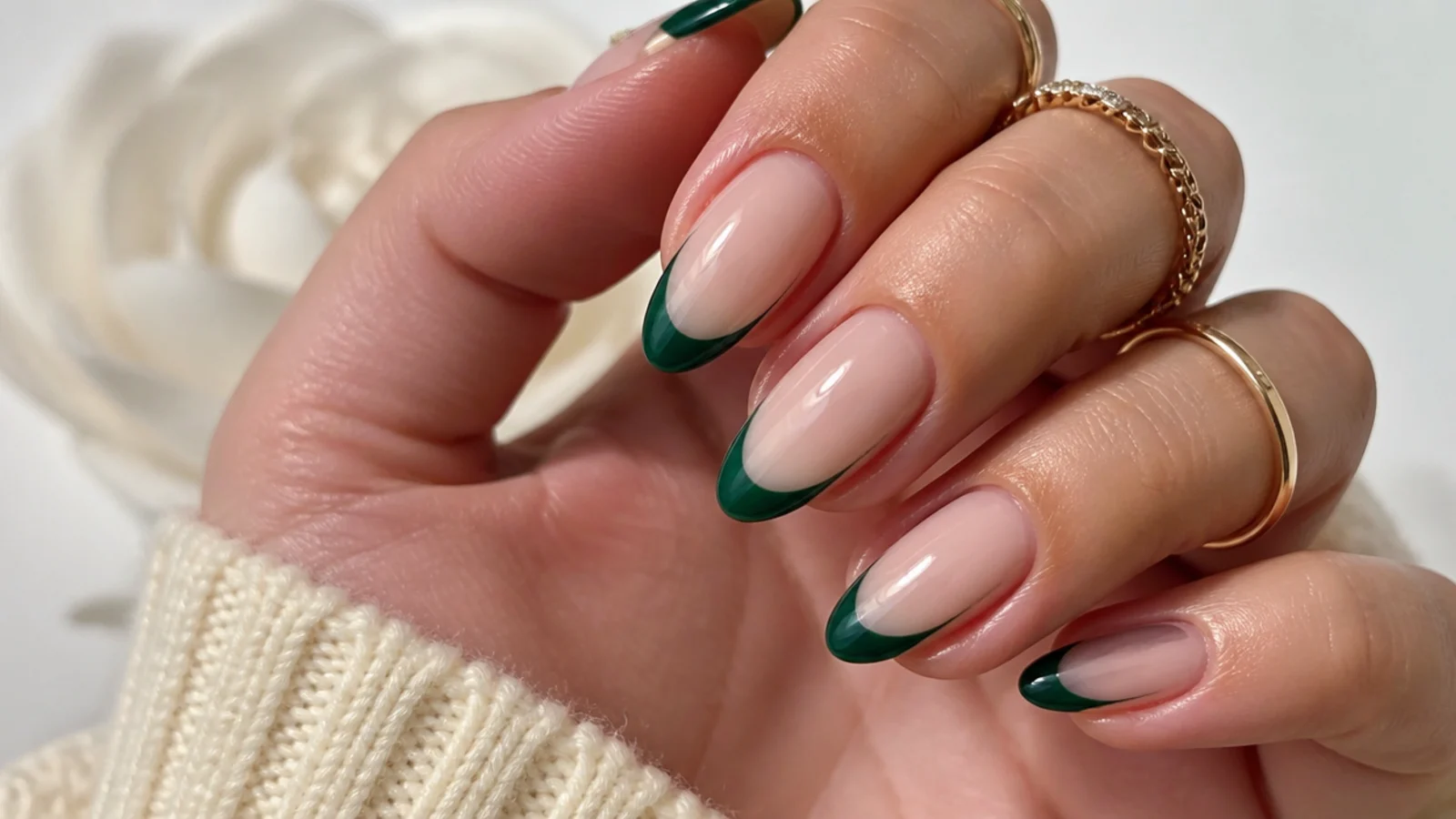 Glossy emerald green french tip nails over a sheer nude base on almond nails