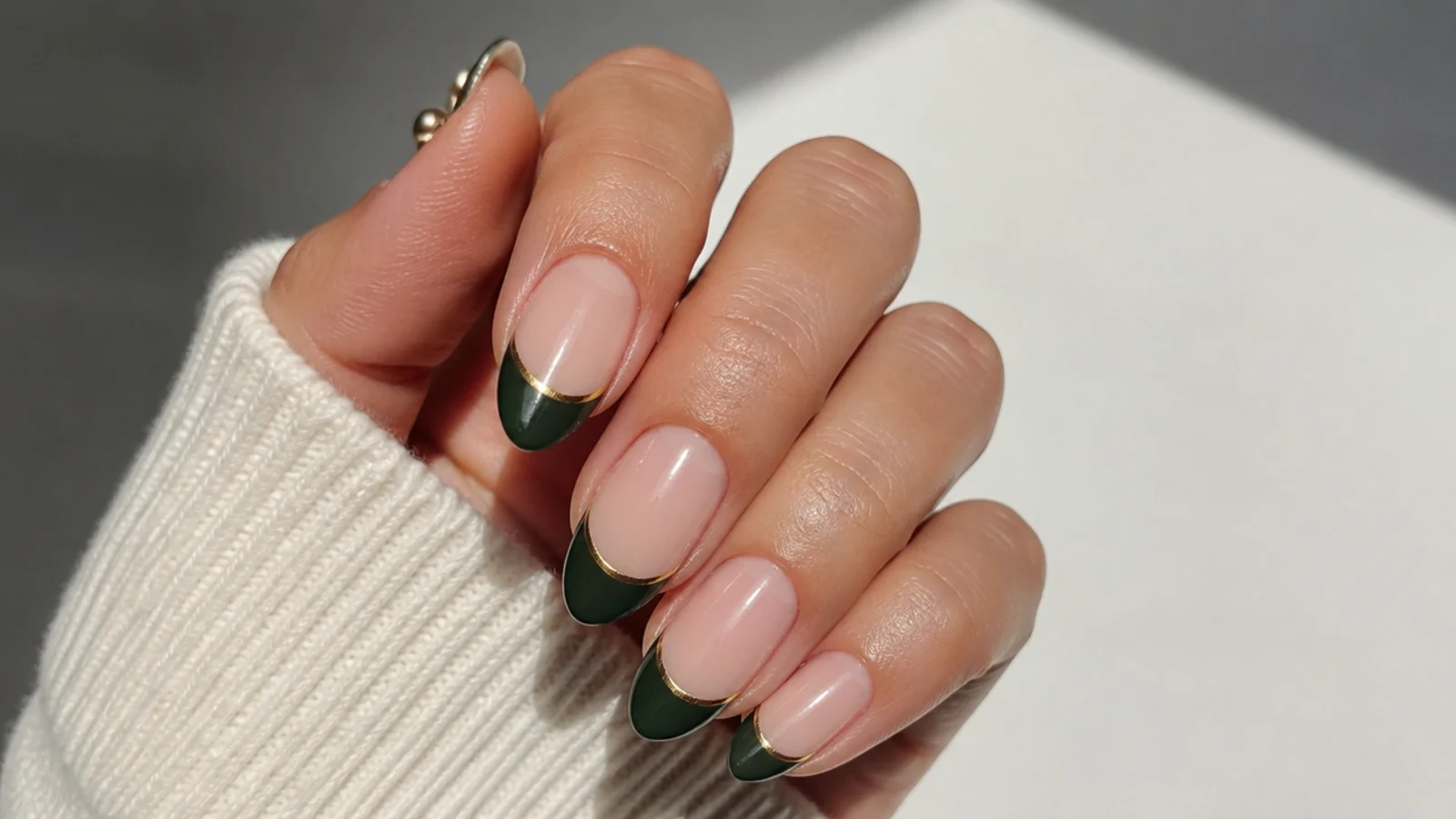 Emerald green french tips with a thin gold line at the smile line on nude nails