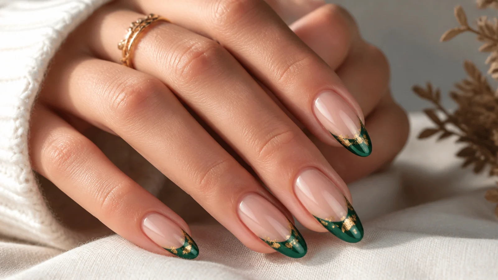 Emerald green french tips scattered with gold leaf flakes on nude nails