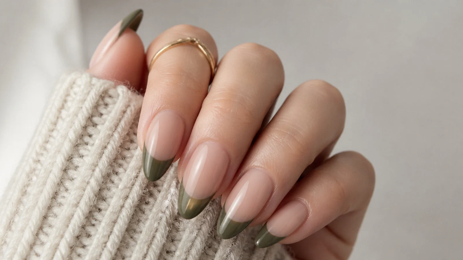 Sage-leaning dark green french tip nails on a soft nude base