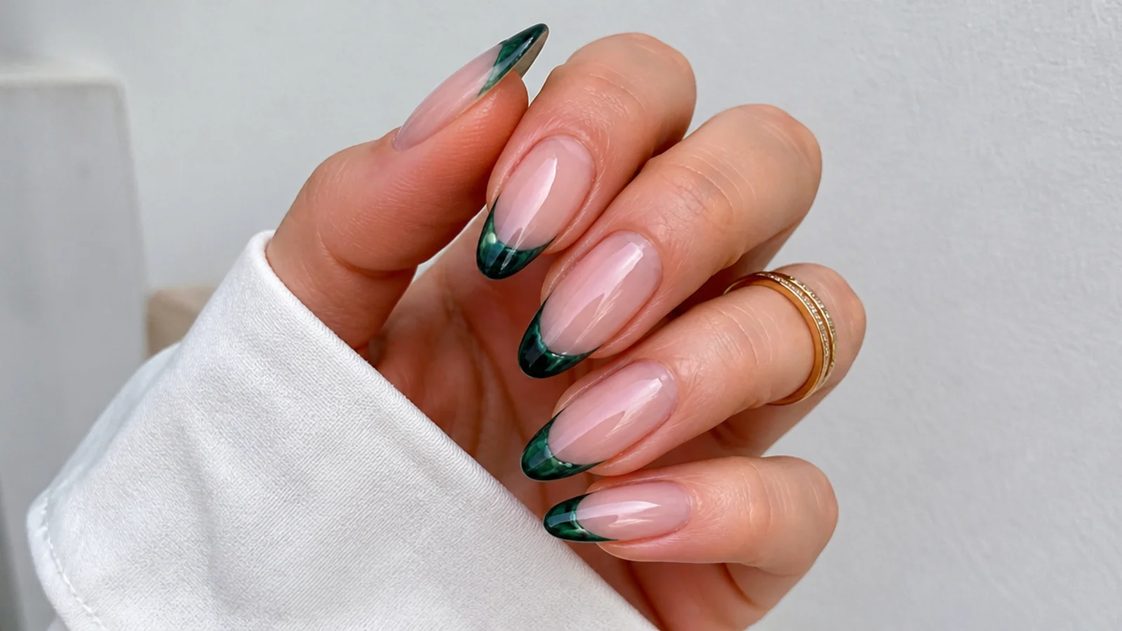 Sheer glass emerald green french tip on almond nails over a nude base