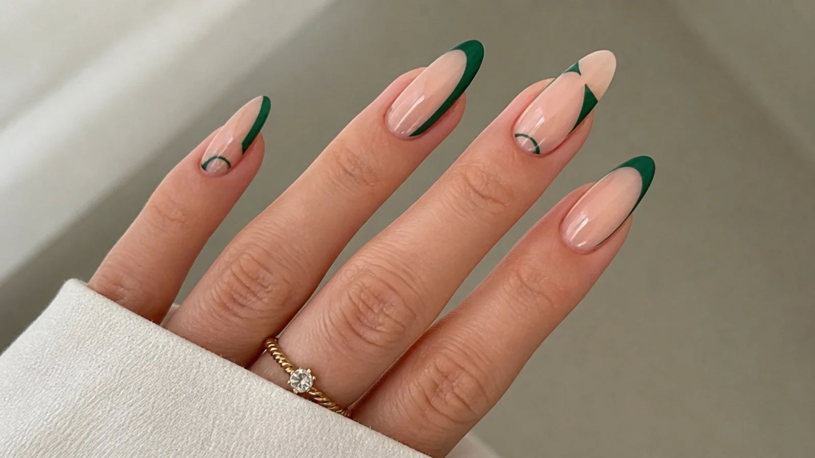 Sheer nude nails with emerald green negative-space geometric accents
