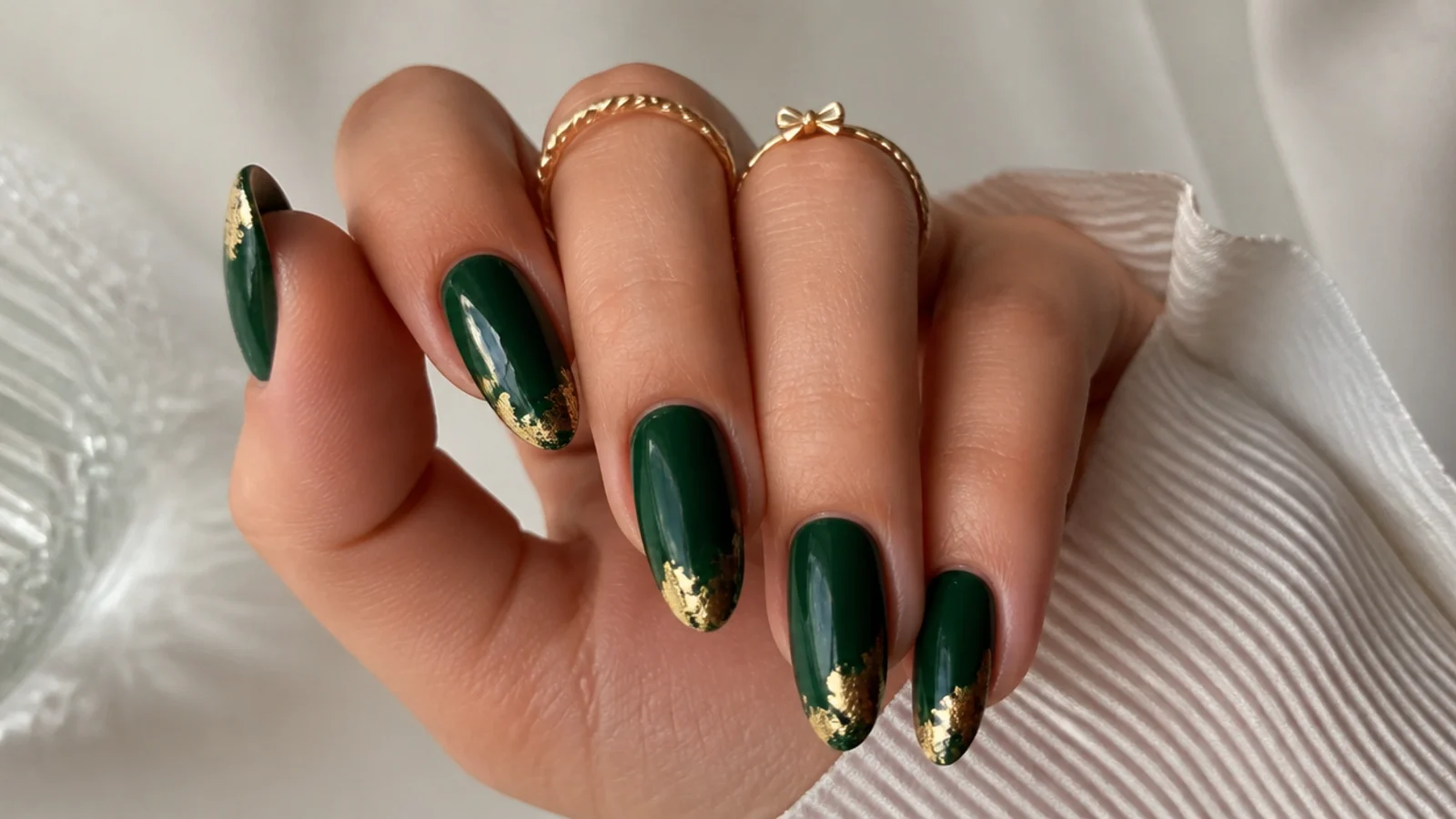 Glossy emerald nails with torn gold foil accents at the tips