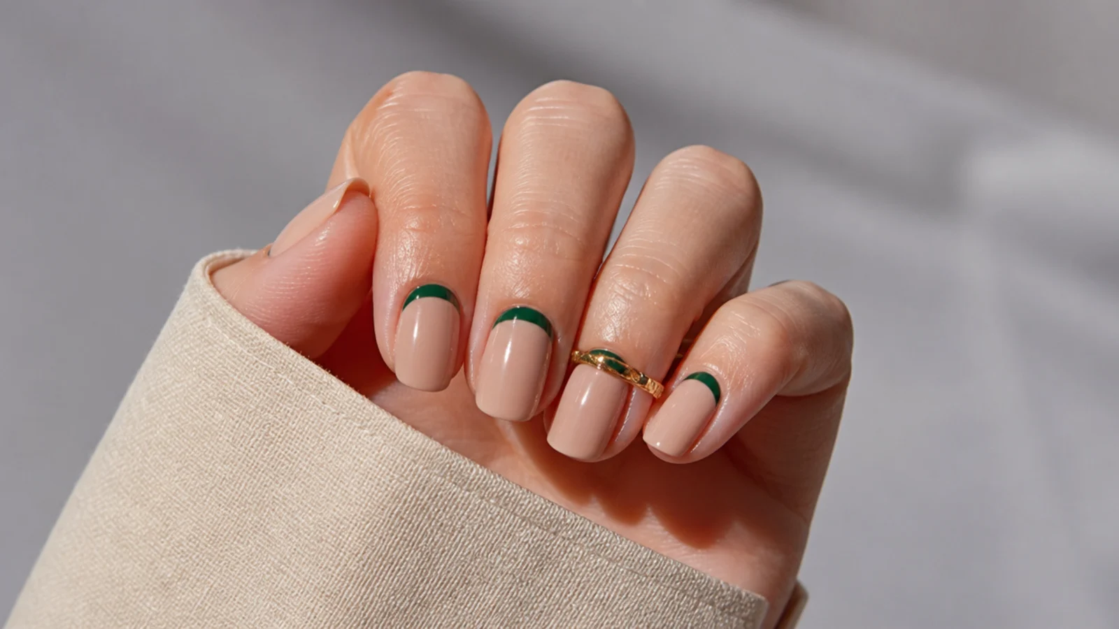 Nude nails with dark green half-moon accents at the cuticle