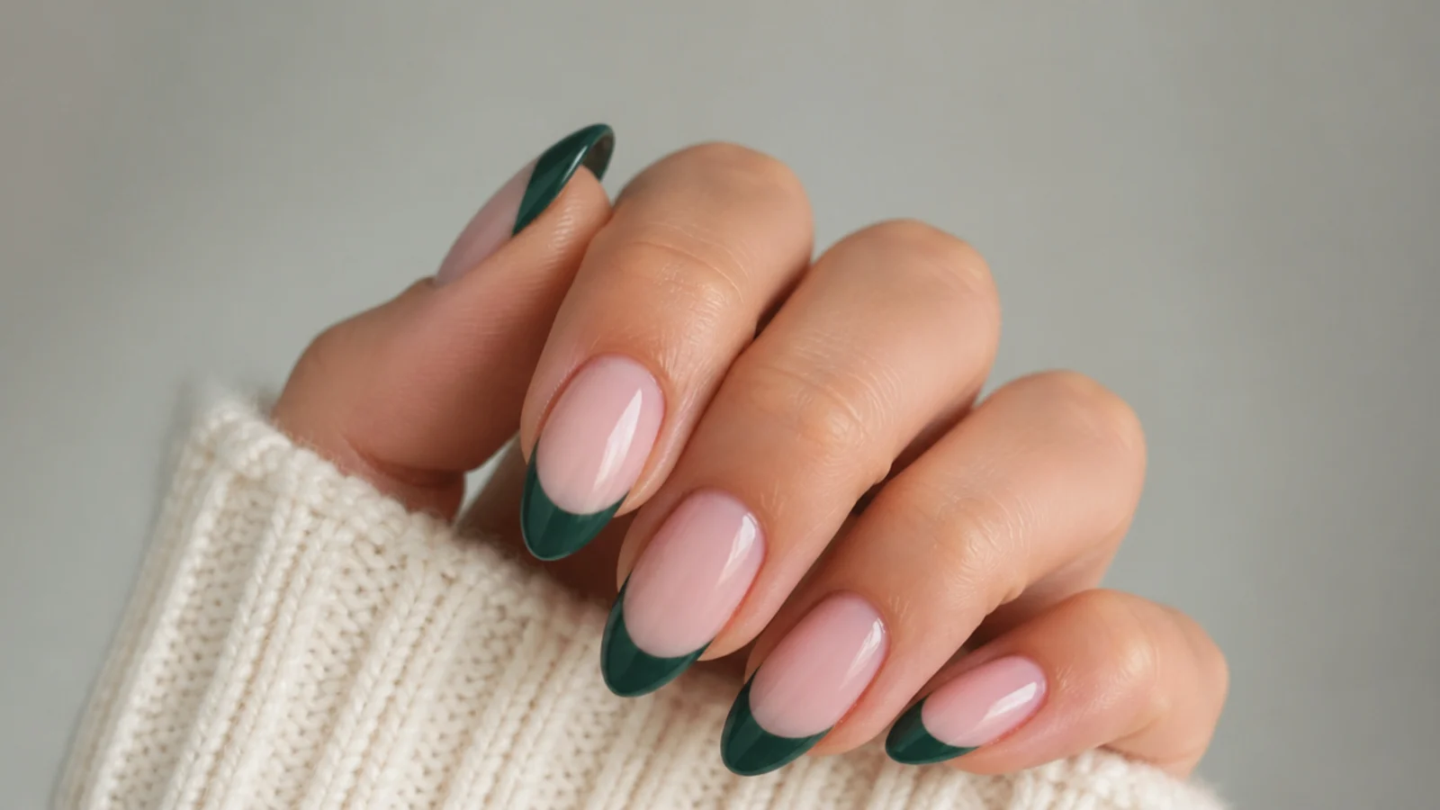Almond nails with dark emerald green french tips over a sheer nude base