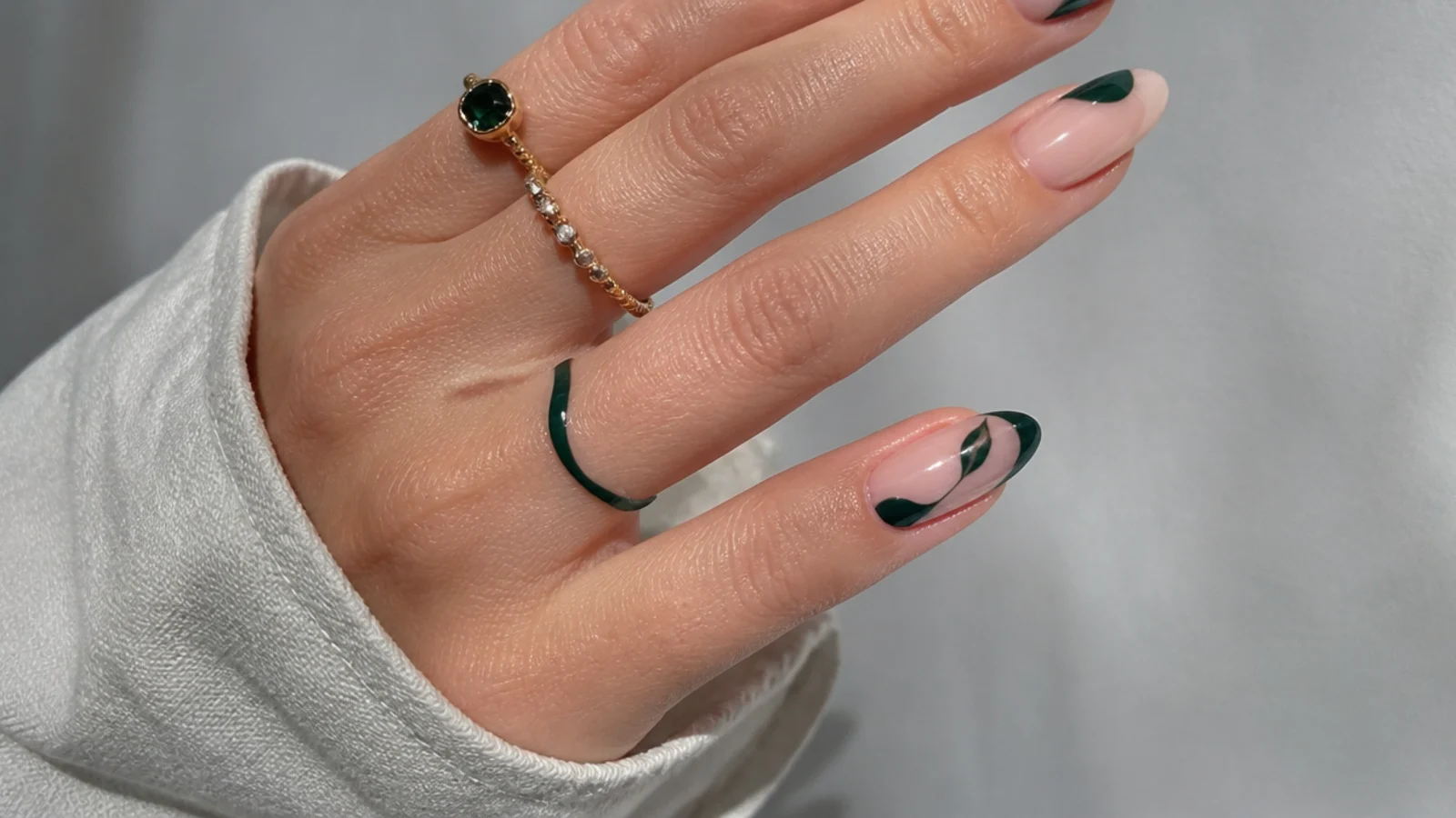 Almond nails with dark emerald negative-space designs over bare nude nails