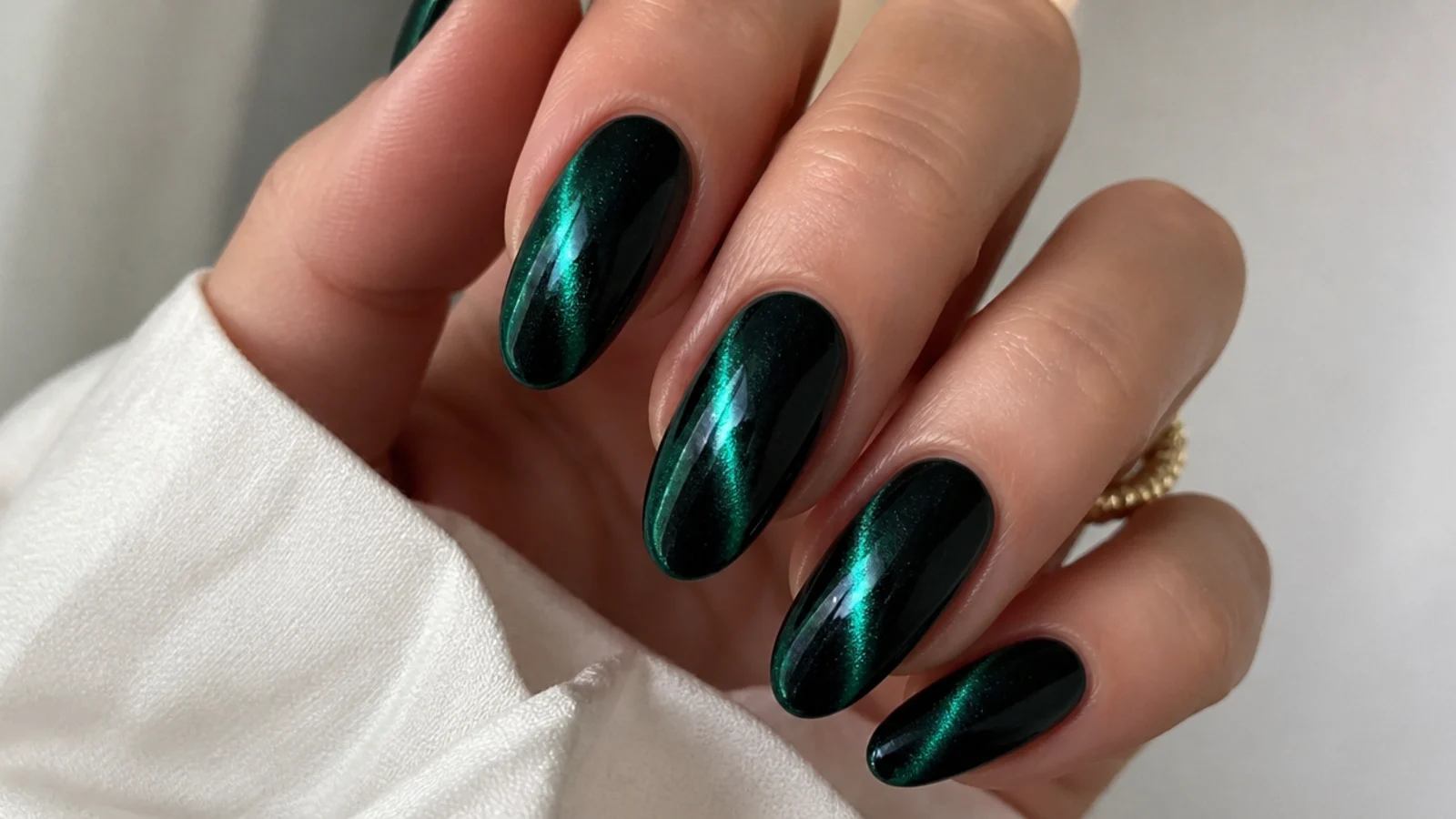 Almond nails in dark emerald cat-eye gel with a bright magnetic light streak